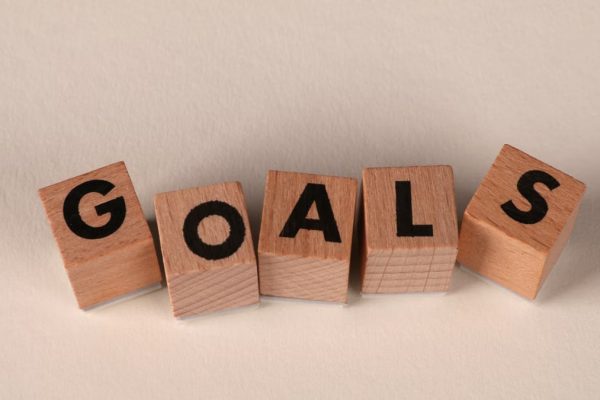 Aligned wooden blocks spelling 'Goals' symbolize target achievement and ambition.
